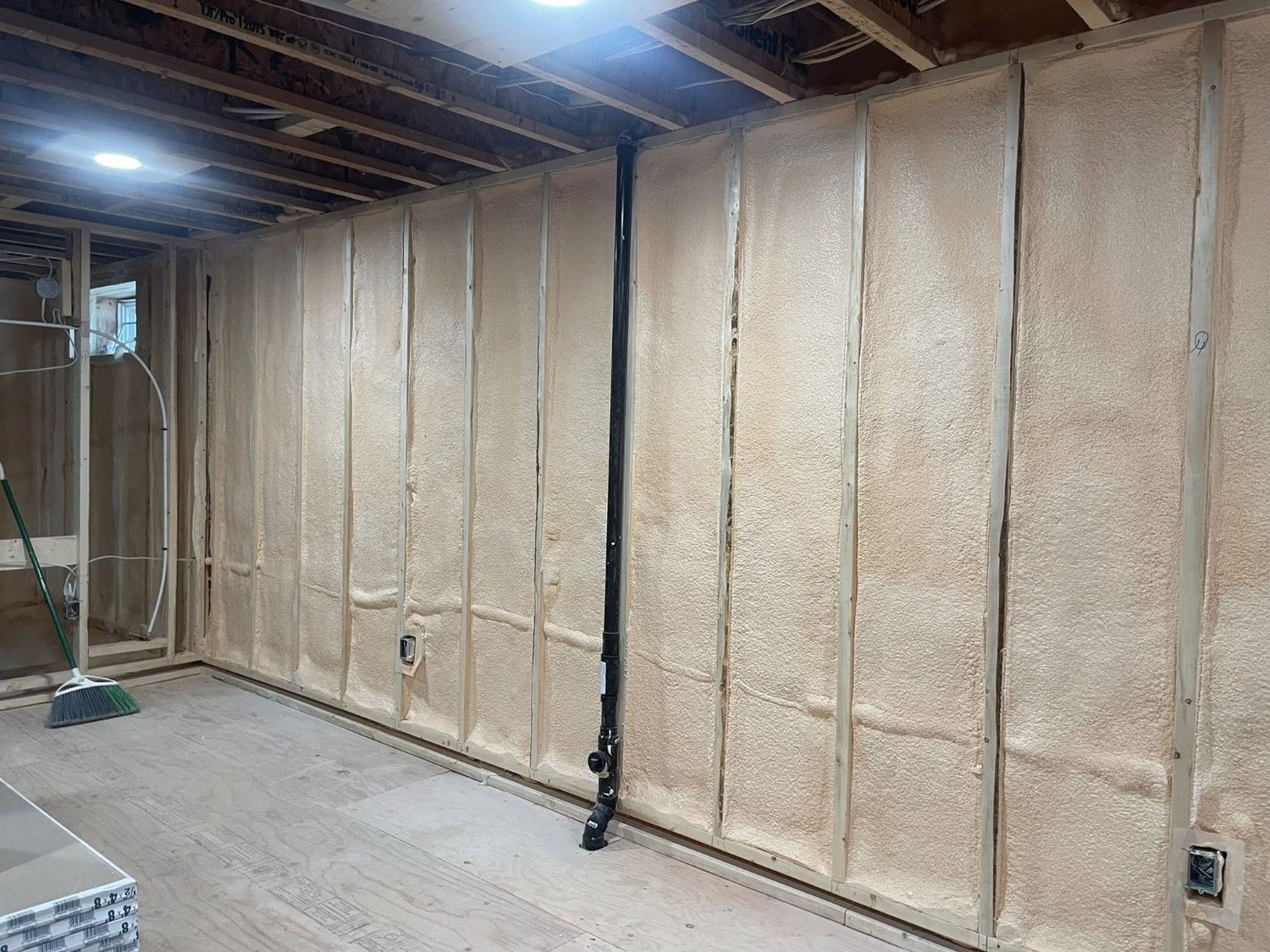 Finished basement wall fully covered in cured spray foam