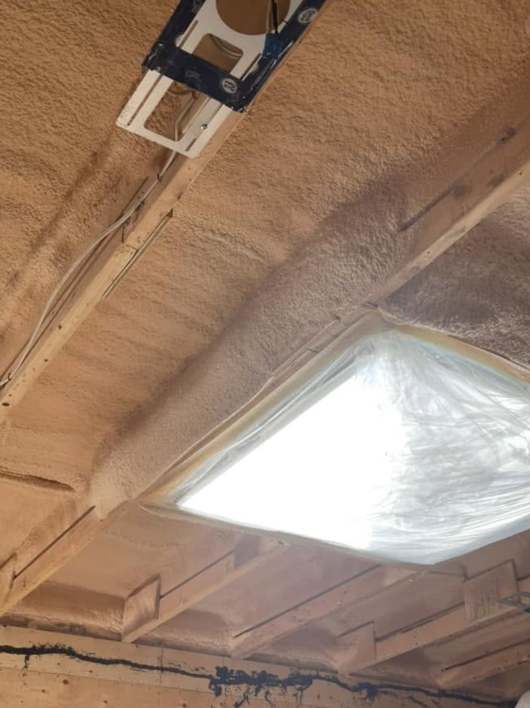 Garage ceiling spray foamed around a recessed potlight fixture
