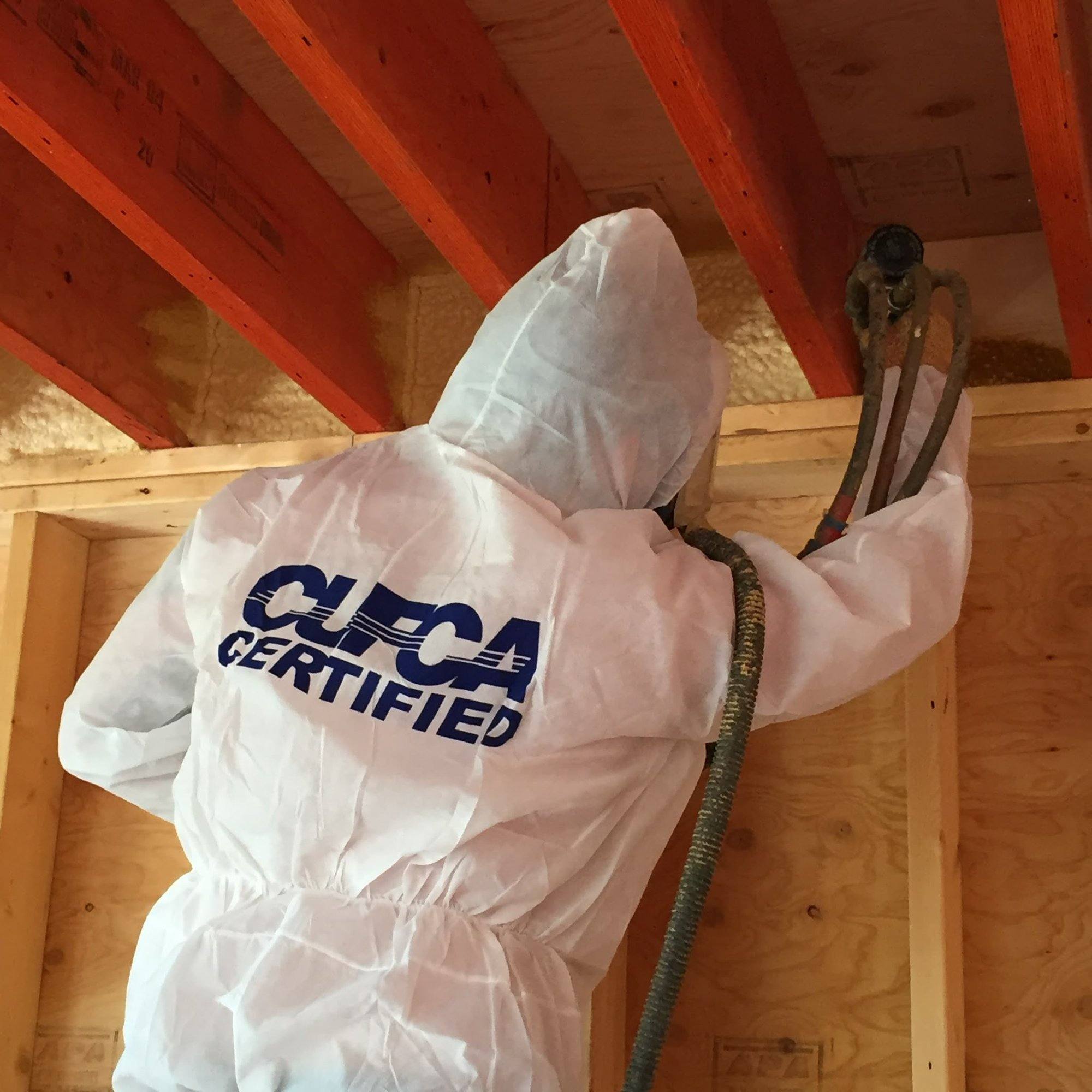 Ecologic installer in a CUFCA Certified coverall spray foaming roof rafters