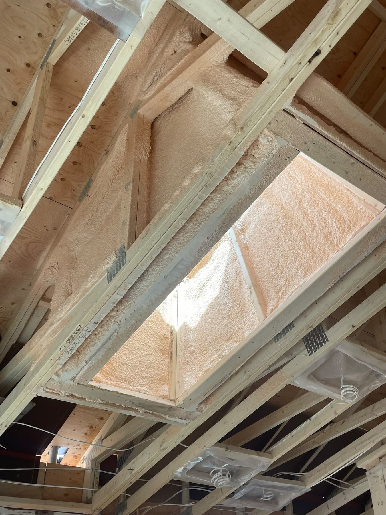 Roof peak dormer framing with closed-cell foam around a skylight rough opening