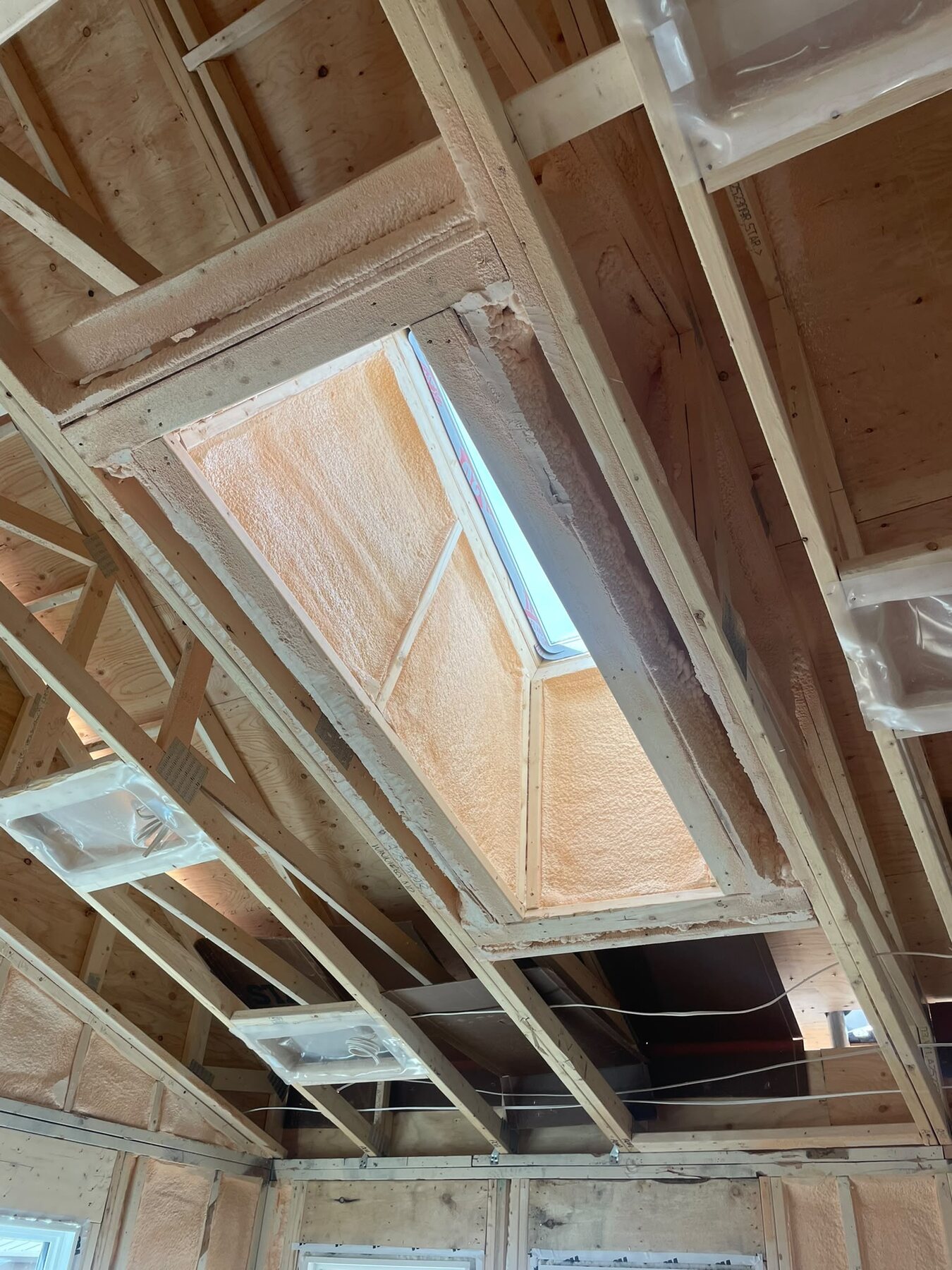Angled skylight shaft foamed in closed-cell spray foam with the window visible at the base