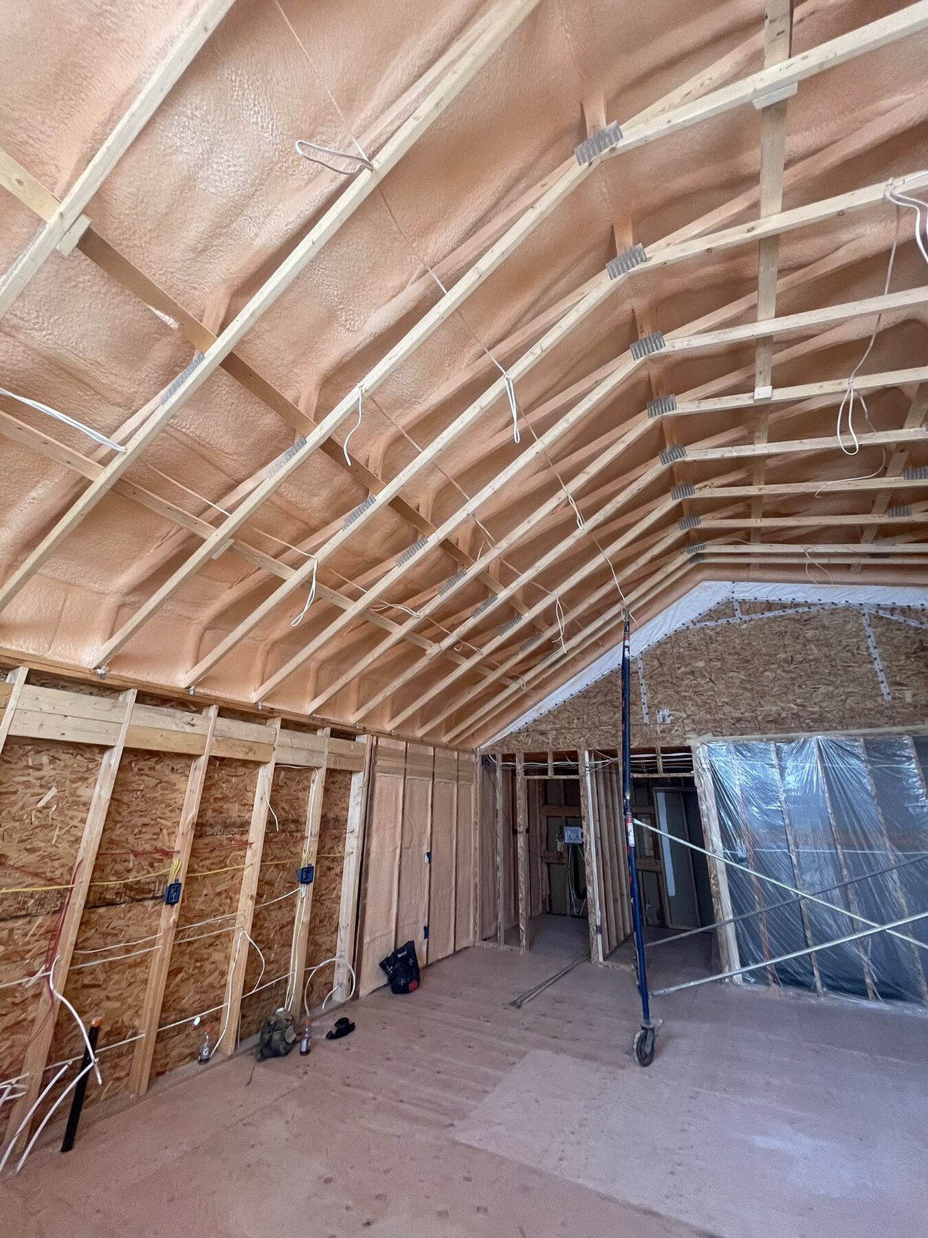 Wide view of a vaulted ceiling and open framed room with closed-cell spray foam applied to the rafters
